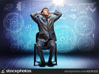 Business mechanism. Young businessman sitting on chair and sketches at background