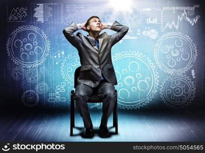 Business mechanism. Young businessman sitting on chair and sketches at background
