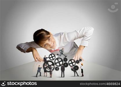 Business mechanisms. Businesswoman leaning on table and looking at businessteam