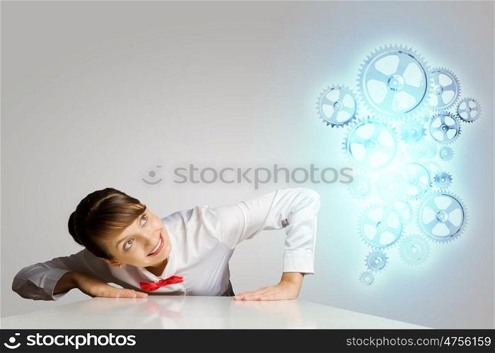 Business mechanisms. Businesswoman leaning on table and looking at cogwheels