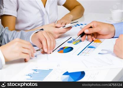 Business meeting. Close up of human hands and documents with graphs and diagrams