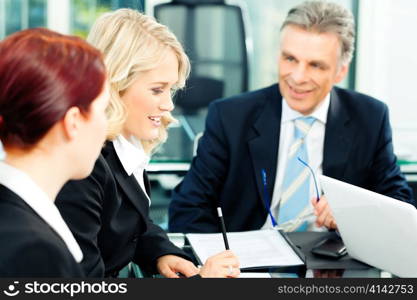 Business - meeting in an office; the businesspeople are discussing a document