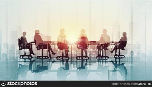 Business meeting in office. Silhouettes of business people sitting at table against office window
