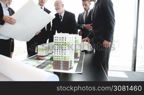 Business meeting of architects and investors looking at model of residential quarter houses