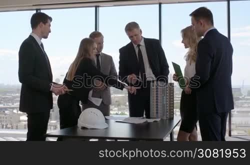 Business meeting of architects and investors, model of modern multi storey residential building house and