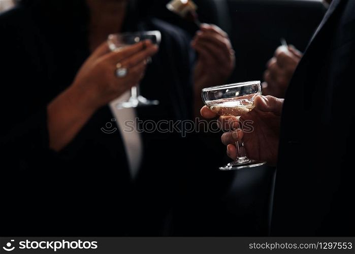 business meeting. successful people in stylish suits holding glasses of alcohol on party, corporate party, conference, forums, banquets, closeup. selective focus. hand with drink of Champagne.. business meeting. successful people in stylish suits holding glasses of alcohol on party, corporate party, conference, forums, banquets, closeup. selective focus. hand with drink of Champagne