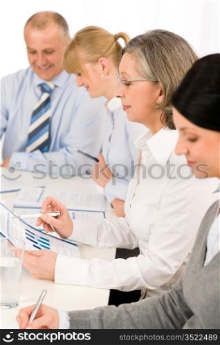 Business meeting team examining sales report sitting around table