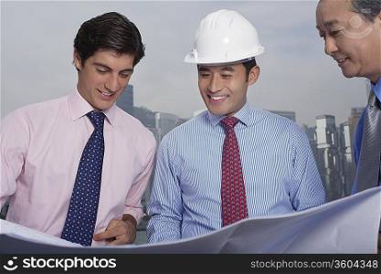 Business men and construction site manager reading blueprints