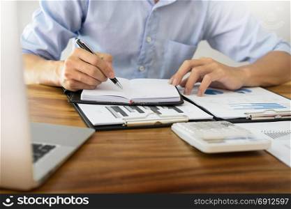 business men working on wooden desk(table) with notebook computer paper, pencil and hand in office, financial concept