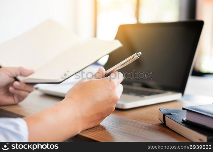 business men working on wooden desk(table) with notebook computer paper, pencil and hand in office, financial concept