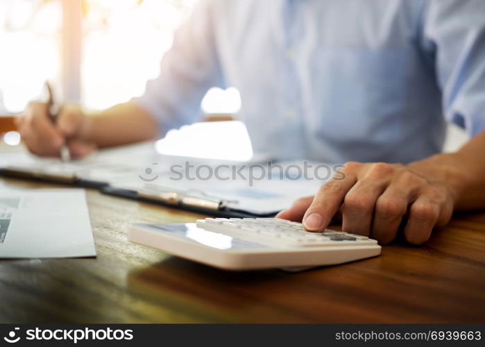 business men working on wooden desk(table) with notebook computer paper, pencil and hand in office, financial concept