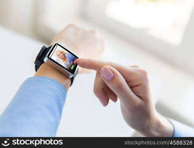 business, modern technology, communication and people concept - close up of female hands setting smart watch with incoming call on screen at office
