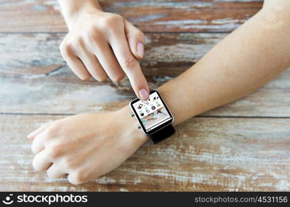 business, modern technology, internet shopping and people concept - close up of female hands setting smart watch with online shop on screen on wooden table