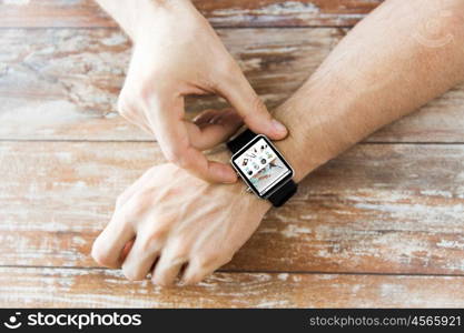 business, modern technology, internet shopping and people concept - close up of male hands setting smart watch with online shop on screen on wooden table