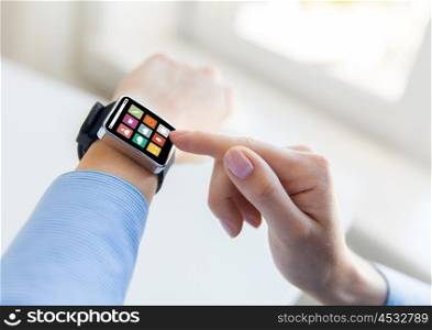 business, modern technology, media and people concept - close up of female hands setting smart watch with menu icons on screen at office