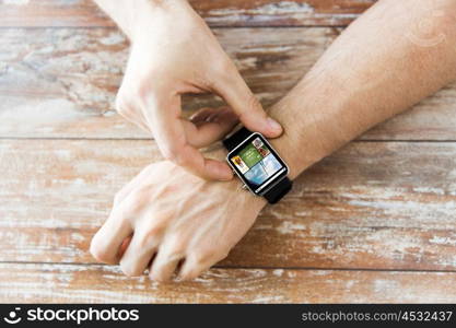 business, modern technology, media, internet and people concept - close up of male hands setting smart watch with news web page on screen on wooden table