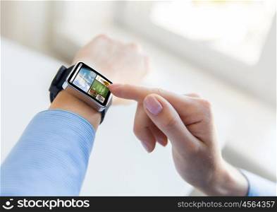 business, modern technology, media, internet and people concept - close up of female hands setting smart watch with news web page on screen at office