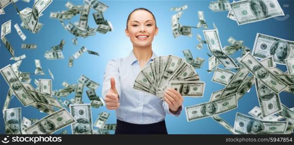 business, money, finance, people and banking concept - smiling businesswoman with heap of dollar cash money showing thumbs up over blue background