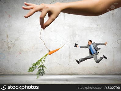 Business motivation. Funny image of businessman chased with carrot