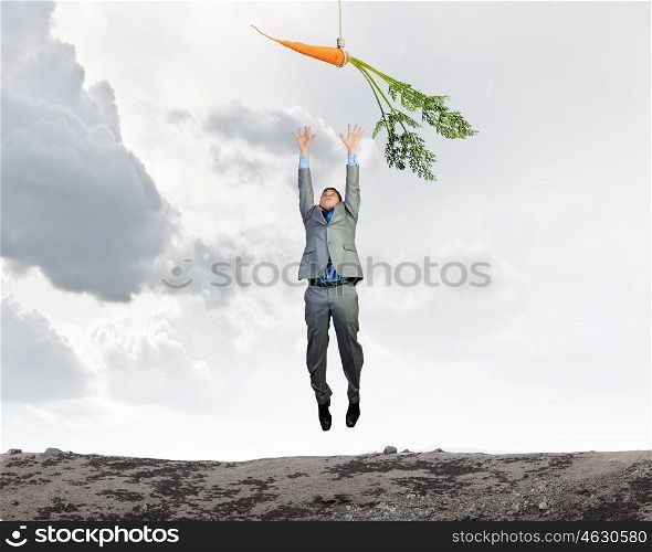 Business motivation. Funny image of businessman chased with carrot