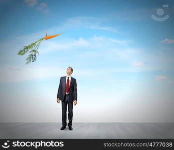 Business motivation. Funny image of businessman chased with carrot