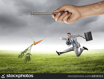 Business motivation. Funny image of businessman chased with carrot