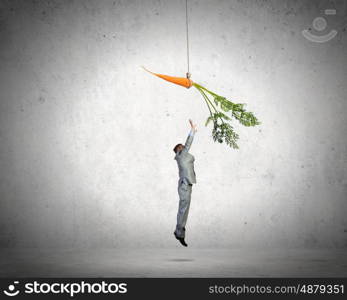 Business motivation. Funny image of businessman chased with carrot