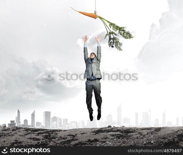 Business motivation. Funny image of businessman chased with carrot