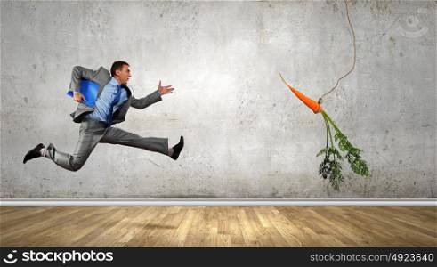 Business motivation. Funny image of businessman chased with carrot
