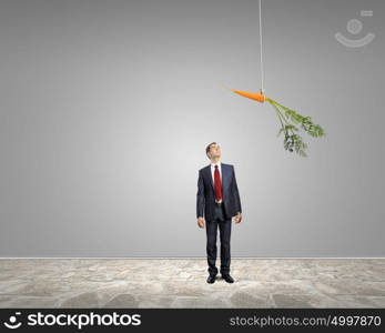 Business motivation. Funny image of businessman chased with carrot