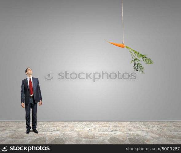 Business motivation. Funny image of businessman chased with carrot