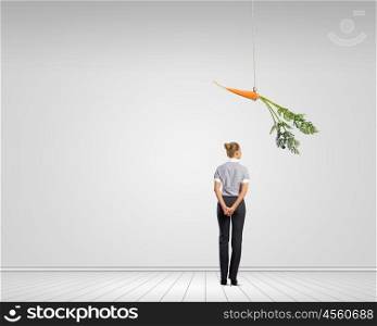Business motivation. Funny image of businesswoman chased with carrot