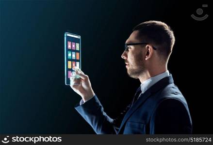 business, multimedia and future technology concept - businessman in glasses working with media icons on transparent tablet pc computer screen over black background. businessman working with transparent tablet pc