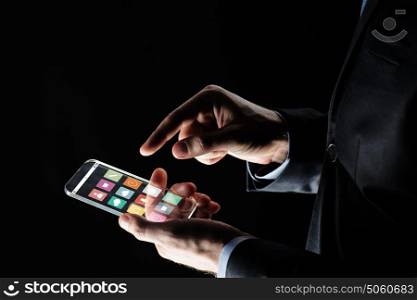 business, multimedia, people and modern technology concept - close up of businessman hands with transparent smartphone with menu icons on screen over black background. close up of businessman hand with glass smartphone