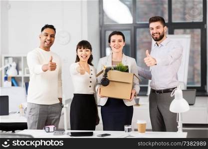 business, new job and corporate concept - female employee with personal stuff and colleagues showing thumbs up at office. new office worker and colleagues showing thumbs up