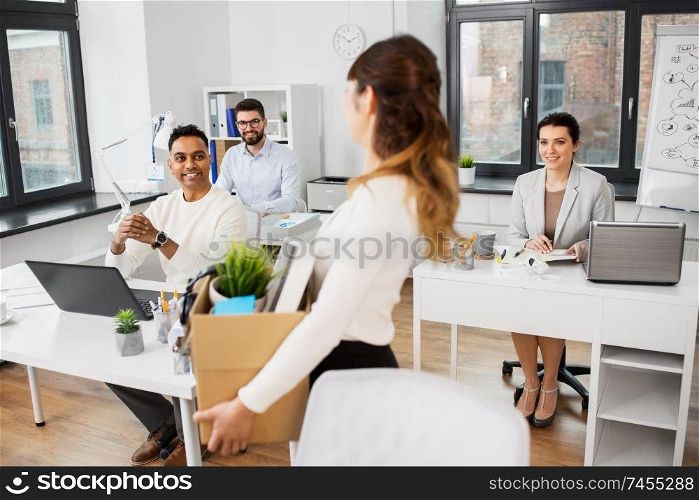 business, new job and corporate concept - happy smiling businesswoman with her personal stuff looking at colleagues at office. happy businesswoman with personal stuff at office
