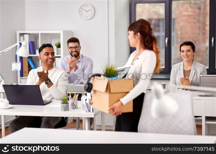 business, new job and quit concept - happy smiling colleagues applauding to female office worker holding her personal stuff. colleagues applauding to new female office worker