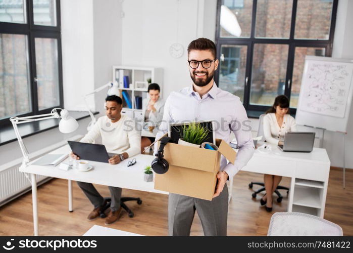 business, new job and quit concept - happy smiling male office worker with personal stuff. happy male office worker with personal stuff