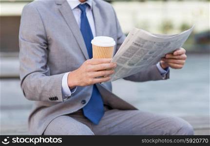 business, news, break and people and concept - close up of businessman reading newspaper and drinking coffee from paper cup over office building