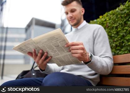 business, news, mass media and people concept - man reading newspaper on city street bench
