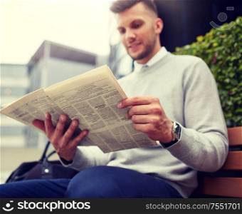 business, news, mass media and people concept - man reading newspaper on city street bench. man reading newspaper on city street bench