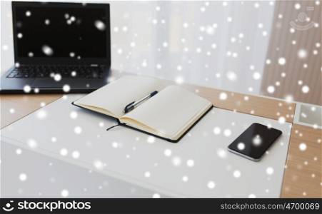 business, objects and education concept - office workplace with notebook, laptop computer and smartphone on table over snow