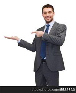 business, office, advertising and people concept - friendly young buisnessman pointing finger to something on the palm of his hand