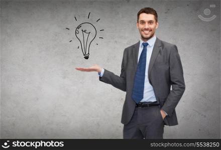 business, office, advertising and people concept - friendly young buisnessman showing light bulb on the palm of his hand