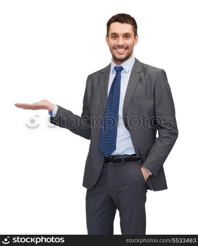 business, office, advertising and people concept - friendly young buisnessman showing something on the palm of his hand