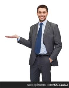 business, office, advertising and people concept - friendly young buisnessman showing something on the palm of his hand