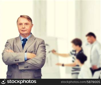 business, office and education concept - serious buisnessman or teacher in suit with team on the back