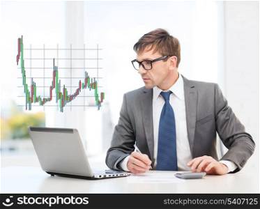 business, office and money concept - businessman in suit and black eyeglasses with laptop computer, papers, calculator and forex chart