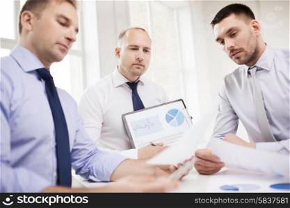 business, office and people concept - serious businessmen with papers in office
