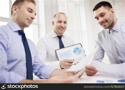 business, office and people concept - smiling businessmen with papers in office